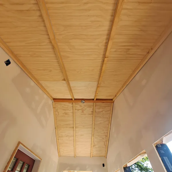 Covered deck ceiling finished in natural beadboard between stained beams